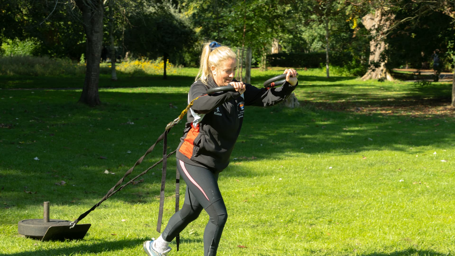 A member pulling a weighted sled across the park
